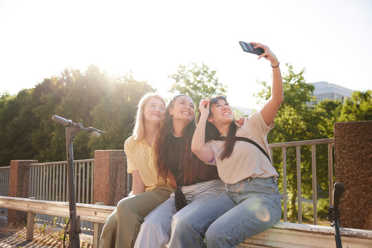 Young female friends spending time together outdoors and taking selfie