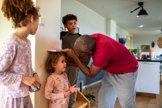 Young Father measuring the height of his child in the living room at home