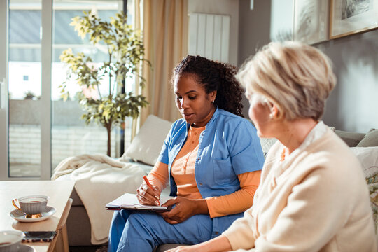 Senior woman consulting her caregiver in the living room at home
