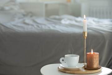 Fototapeta na wymiar white cup of coffee with candles on table indoor