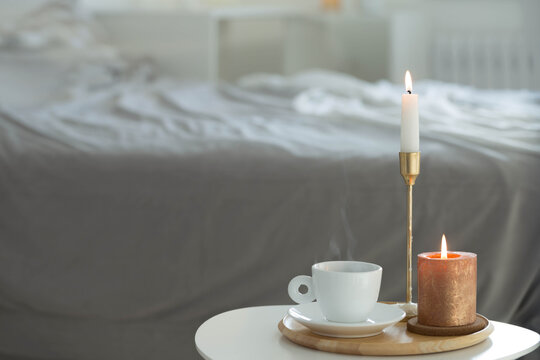 white cup of coffee with candles on table indoor