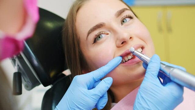 Dentist performing teeth grinding procedure in dental clinic. Woman visits doctor grinding teeth to create perfect smile in private hospital