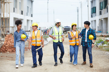 workers or architect walking and talking about work on the construction site