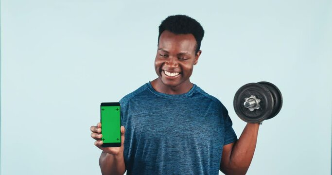 Happy black man, phone and dumbbell with green screen for fitness app against a studio background. Portrait of African active male person or bodybuilder smile with mobile smartphone display or mockup