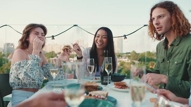 Positive multinational friends celebrate holiday and eating at open air table in restaurant
