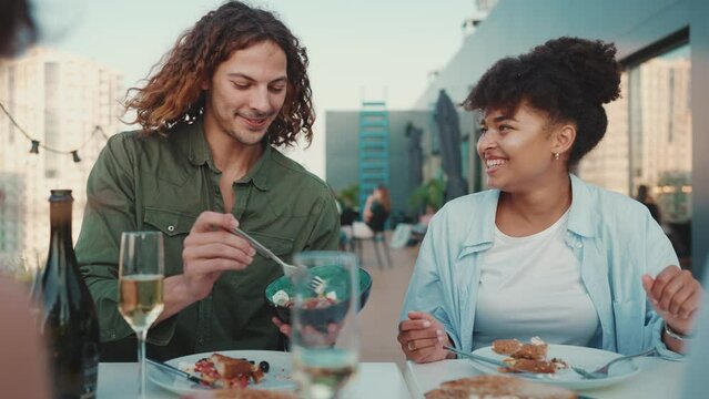 Cute Multinational Friends Celebrate Holiday And Eating At Open Air Table In Restaurant