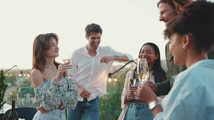 Laughing multicultural friends talking while celebrating birthday on restaurant balcony