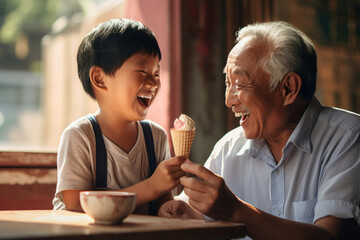 Cheerful Asian grandfather and grandchild eating ice cream outdoors on sunny summer day. Granddad sharing a dessert with a child in outdoor cafe. - obrazy, fototapety, plakaty