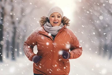Foto op Plexiglas Young plus size woman running in city park on snowy winter day. Overweight young girl jogging in the street. Weight loss concept. © MNStudio