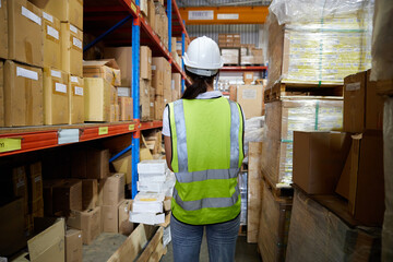 back view worker looking at cardboard box on shelf in warehouse storage