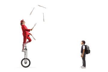 Schoolboy watching an acrobat riding a giraffe unicycle and juggling