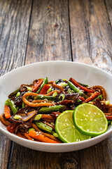 Asian food - roast beef, noodles and stir fried vegetables on wooden table
