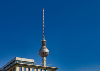 Nahaufnahme der Kugel und Antennenspitze des Berliner Fernsehturms vor strahlend blauem Himmel über einem modernen Gebäude, Berlin, Deutschland © Mark Lämmchen 