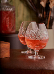 Glasses of brandy on a rustic table with a decanter in the background.