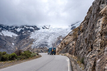 Green camper on a road with a glacier behind it