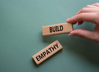 Build empathy symbol. Wooden blocks with words Build empathy. Psychologist hand. Beautiful grey...