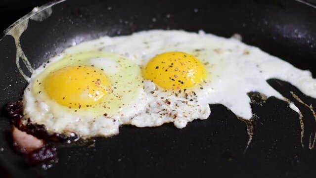 Raw eggs frying on a pan, close up, organic breakfast.