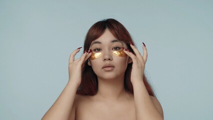 Close-up isolated photo of a young seminude woman with red dyed hair and nude makeup fixing and...