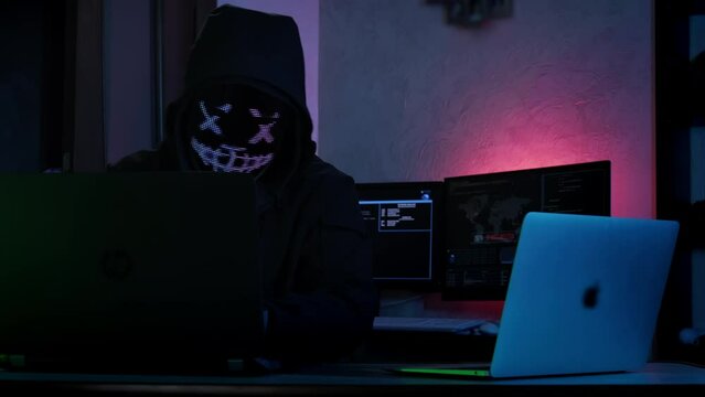 Unrecognizable hacker man in mask typing on keyboard and engaging hacking into security systems