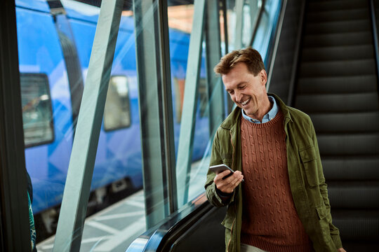 Middle aged man using his smartphone while on the escalator at the train station