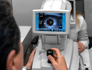 Lady looking at refractometer eye testing machine in ophthalmology, tonometer, refractometer. Eye examination for glasses or lenses prescription. Ophthalmologist Ophthalmic Exam Concept. optometrist