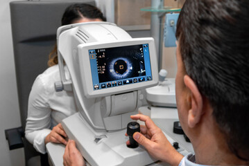 Lady looking at refractometer eye testing machine in ophthalmology, tonometer, refractometer. Eye examination for glasses or lenses prescription. Ophthalmologist Ophthalmic Exam Concept. optometrist - obrazy, fototapety, plakaty