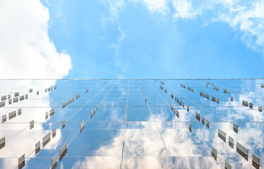 Beautiful blue sky with white clouds reflected in the glass surface of the wall with small metal rectangular plates