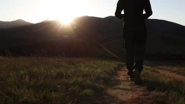 Homem caminhando com celular na m&atilde;o, na natureza