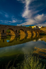 Roman bridge of Mérida in vanishing point perspective over the Guadiana River, illuminated by...