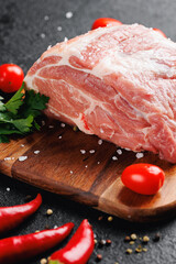 Fresh and raw meat filet neck of pork on wooden board on dark background, steak top view