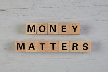 wooden blocks  in a white and grey board with the text money matters