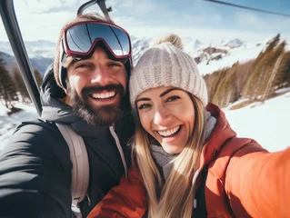 Stickers muraux Gondoles Portrait of happy couple on a gondola at a ski resort make selfie , snowy mountain landscape on background.