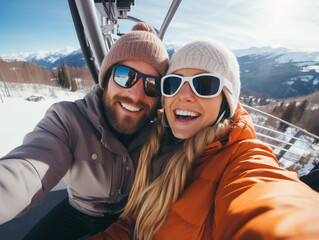 Portrait of happy couple on a gondola at a ski resort make selfie , snowy mountain landscape on background.