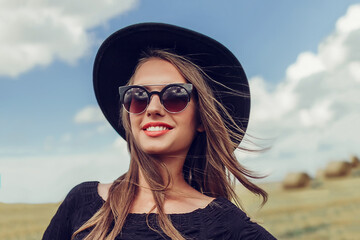 Gorgeous young beautiful happy smiling woman portrait in black hat and sun glasses outdoors	