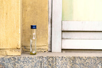 A small empty bottle of alcohol stands on the windowsill