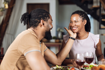 Affectionate black woman flirting with her boyfriend during meal at dining table