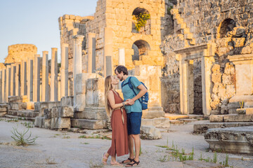 Obraz premium Loving couple of tourists at the ruins of ancient city of Perge near Antalya Turkey. Traveling with kids concept