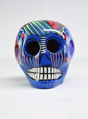 Vista frontal de colorido y hermoso cráneo azul de cerámica pintada, tradicional artesanía Oaxaqueña muy utilizada en ofrendas de día de Muertos en México.