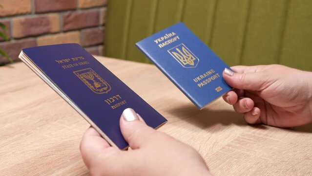Israeli passport and Ukrainian passport in hands. Shekels and hryvnias, the national currency. Concept: repatriation, change of citizenship, aliyah, absorption basket.