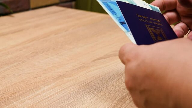 Israeli passport and Ukrainian passport in hands. Shekels and hryvnias, the national currency. Concept: repatriation, change of citizenship, aliyah, absorption basket..