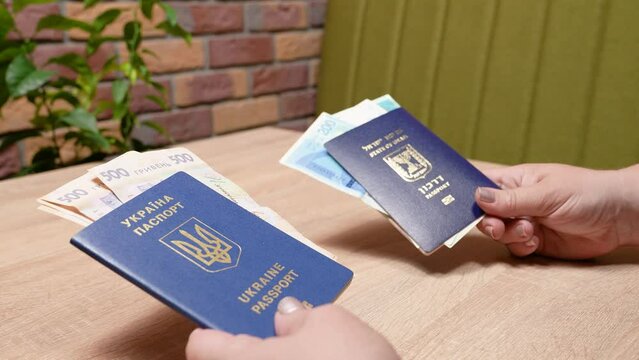 Israeli passport and Ukrainian passport in hands. Shekels and hryvnias, the national currency. Concept: repatriation, change of citizenship, aliyah, absorption basket.