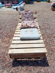 Wooden lounger and cushions on the Sinai Peninsula. Front view of empty sun lounger. Chill out and...