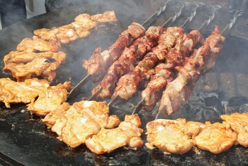 Kebab meat skewers grilling and chicken on fire at backyard. Marinated shashlik, meat grilling on metal skewer. Greek grill food. Outdoor barbecue cooking. Street food concept