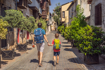 Fototapeta na wymiar Happy father and son tourists on background of old street of Antalya. Traveling with kids concept. male tourist traveler discover interesting places and popular attractions and walks in the old city