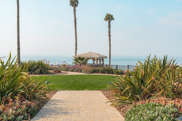 Obraz premium A tropical paradise with a gazebo nestled among swaying palm trees, and beautiful Pacific Ocean