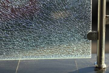 Close up of a shattered glass fence in the city.