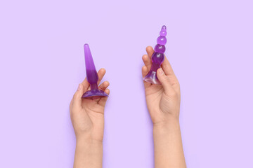 Woman with anal plugs from sex shop on lilac background
