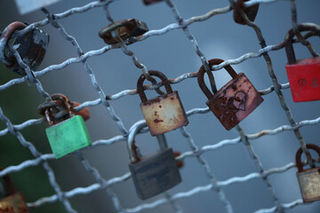 Old and new locks with names and dates written on them couples connection in love lock on a bridge...