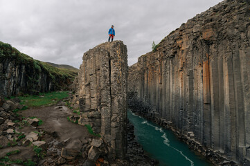 A man standing on a cliff and watching the canyon from the top.