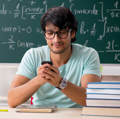 Young male student mathematician in front of chalkboard